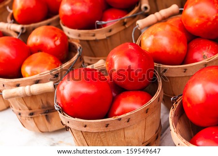 Display of locally grown red tomatoes in small bushel basket for sale at local farmers market