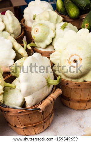 Fresh locally grown patty pan squash in small bushel baskets on display at local farmers market