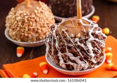 Display of decorated hand dipped caramel apples sitting on orange napkin with candy corn