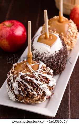 Line of 3 hand dipped caramel covered apples sitting on rectangular white plate
