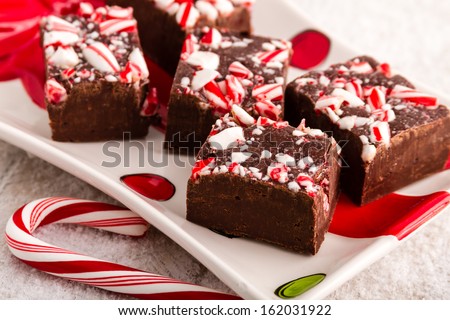 Homemade candy cane fudge on festive holiday plate with large candy cane