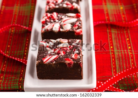 Candy cane fudge sitting on white plate with red ribbon