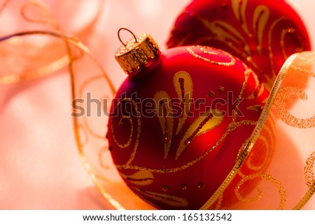 Close up of red and gold glitter Christmas ornaments with sheer gold ribbon