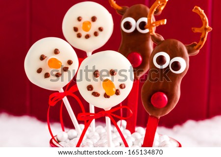 Snowmen and reindeer cookie pops against red background