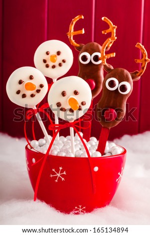 Snowmen and reindeer cookie pops in red snowflake bowl