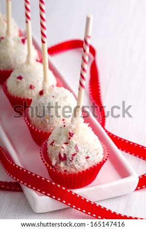 Row of peppermint brownie cake pops standing red cups on white plate with red ribbon