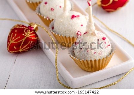 Row of peppermint brownie cake pops standing gold glitter cups on white plate with gold ribbon