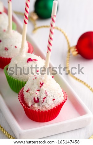 Row of peppermint brownie cake pops standing red and green cups on white plate with gold ribbon