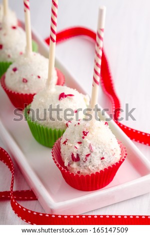 Row of peppermint brownie cake pops standing red and green cups on white plate with red ribbon