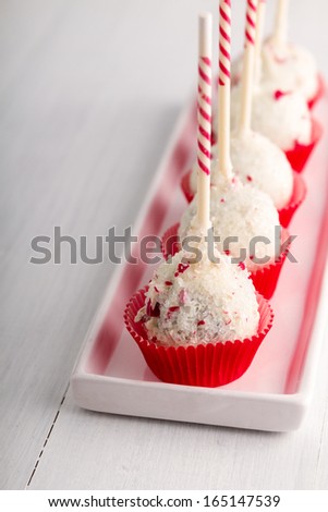 Row of peppermint brownie cake pops standing red cups on white plate