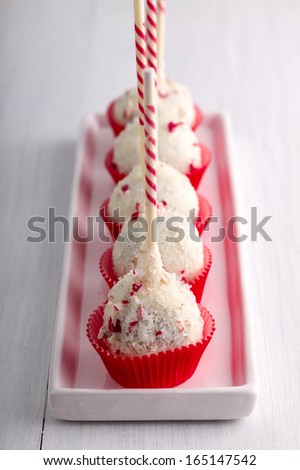 Row of peppermint brownie cake pops standing red cups on white plate