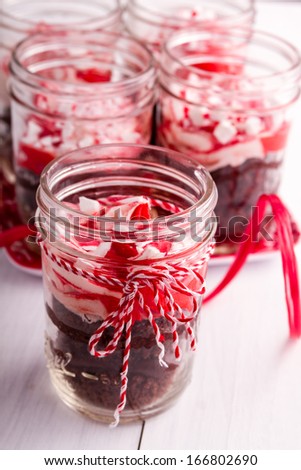 Chocolate peppermint cupcakes in a jar with red and white bakers twine sitting on red plate and white wood table