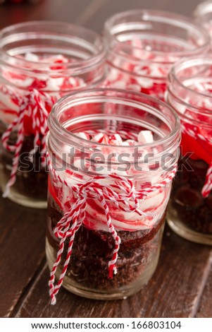 Chocolate peppermint cupcakes in a jar with red and white bakers twine sitting on old brown table