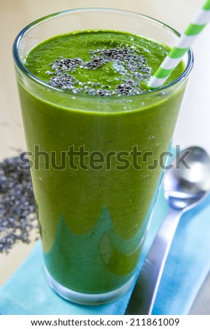 Healthy green fresh fruit and vegetable juice smoothie with green striped straw and chia seeds heart garnish
