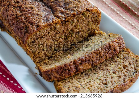 Close up of loaf of homemade zucchini bread sitting on white plate with red striped napkin