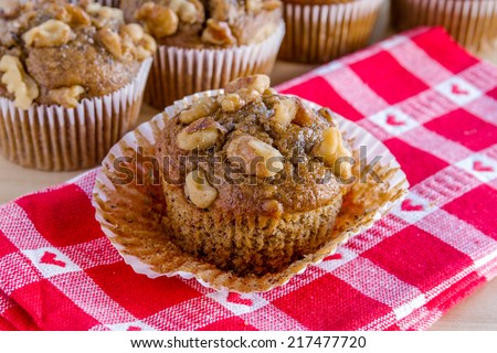 Close up of fresh baked banana walnut and chia seed muffin with paper removed sitting on red heart napkin