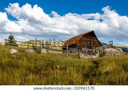 Historic Moore Barn in Steamboat Springs Colorado with mountain slopes filled with fall color on warm autumn afternoon