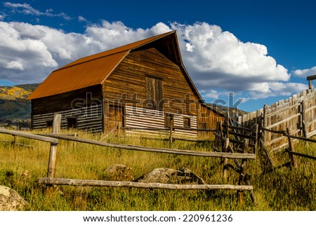 Historic Moore Barn in Steamboat Springs Colorado with mountain slopes filled with fall color on warm autumn afternoon