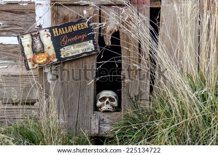Creepy Halloween skull in old abandoned wood building with Halloween greetings sign