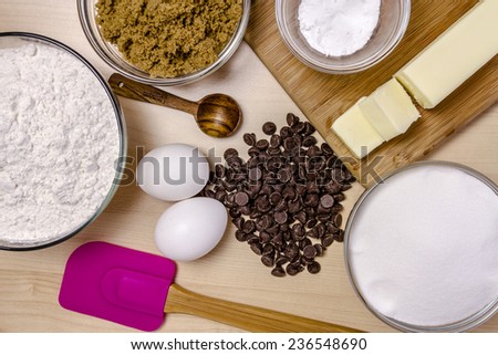 Ingredients for making homemade chocolate chip cookies with pink spatula