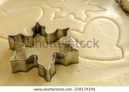 Close up of snowflake and mitten cookie cutters cutting out holiday sugar cookies