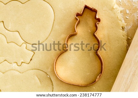 Close up of snowman copper cookie cutter sitting in holiday sugar cookie dough