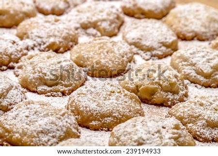 Rows of potato chip cookies sprinkled with powdered sugar sitting on wax paper