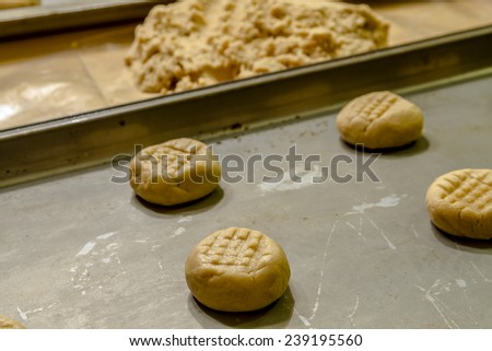 Rows of peanut butter cookie dough balls on baking pans sitting on counter waiting to be baked