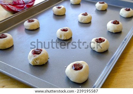 Rows of raspberry thumbprint cookies sitting on baking sheet waiting to go into oven