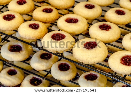 Rows of raspberry thumbprint cookies cooling on wire baking rack sitting on counter top
