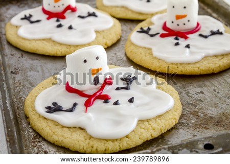Close up of melting snowman sugar cookies sitting on metal baking pan