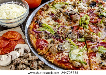 Close up of fresh baked thin crust supreme pizza surrounded by sausage, pepperoni, mushrooms, cheese and tomato ingredients