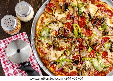 Sliced fresh baked thin crust supreme pizza with fresh mushrooms, onions, green peppers, tomato sauce, pepperoni, sausage and cheese with heart napkin and pizza cutter