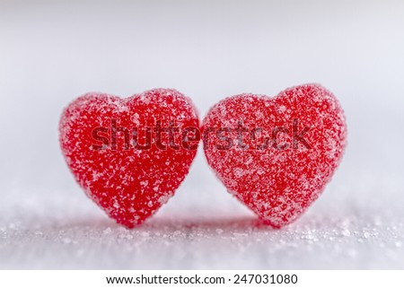 Two cinnamon heart candies coated with sugar sitting on white background