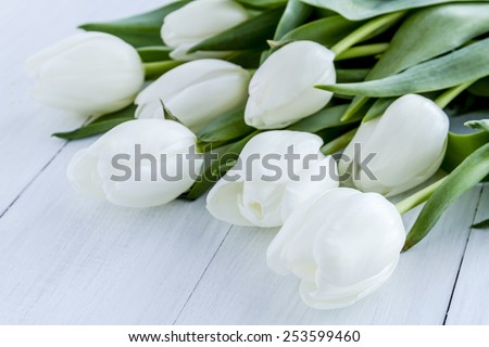 Bouquet of white tulips laying on white wooden table