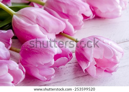 Close up of bouquet of pink tulips laying on antique pink wooden table
