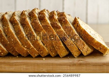 Slices of whole grain and seeds fresh baked bread sitting on wooden cutting board