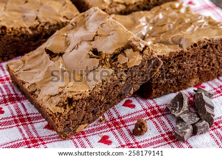 Homemade double chocolate chunk brownies sitting on white checked napkin with red hearts