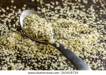 Organic hemp seeds on silver spoon sitting on dark wooden table