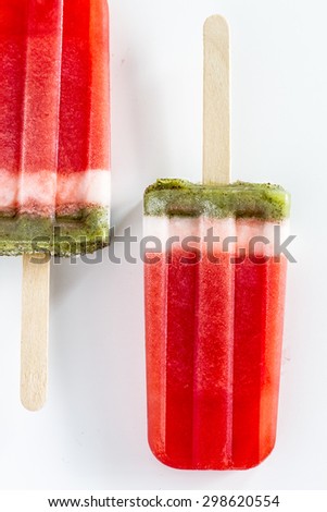 Close up of 2 frozen fresh fruit watermelon and kiwi popsicles sitting on white background