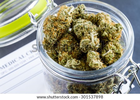 Close up of medical marijuana buds in glass container on black background