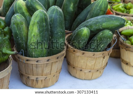 Fresh organic cucumbers in brown bushel baskets sitting on table at local farmers market