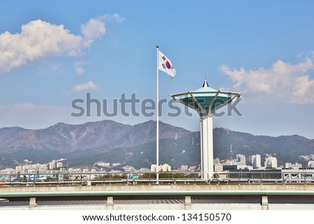 Korean flag and traffic control tower with clouds, mountain and blue skies.