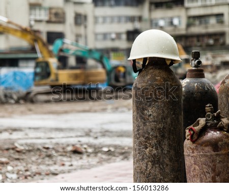Hardhat on a gas cylinder at a construction site with rubble and trucks demolishing