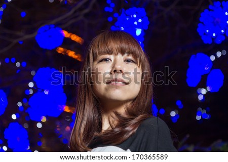 Pretty Japanese female in front of blue bright decorations
