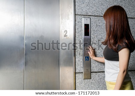 Female at an elevator pushing button