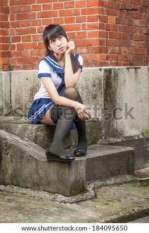 Chinese schoolgirl on stairs of red brick school building