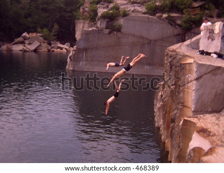 Cliff diving. Three men in the air diving into a rock quarry.