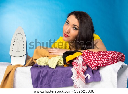 Houseworks, woman with pile of clothes for ironing, on blue background