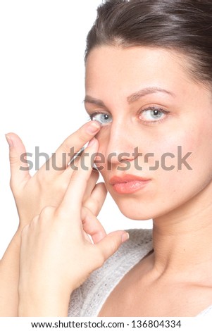 Young woman inserting contact lenses to eye